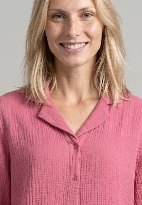 Mousselineblouse met bowlingkraag blush berry Een glimlachende vrouw met blond haar draagt een roze, gestructureerde blouse.