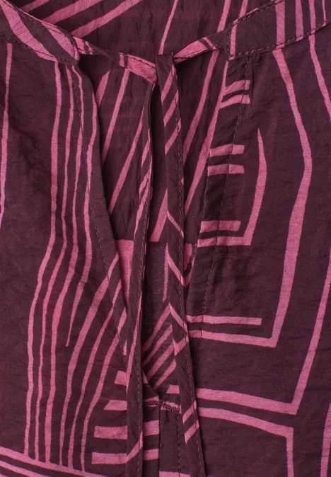 Blouse met korte mouwen, split in de hals en print blush berry Donkerviolette stof met roze geometrisch streeppatroon en bindceintuur.