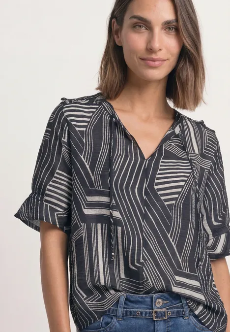 Blouse met korte mouwen, split in de hals en print darkest blue Vrouw in zwart-wit grafisch gemêleerd overhemd met geometrisch patroon en spijkerbroek.