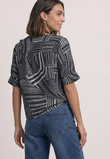Blouse met korte mouwen, split in de hals en print darkest blue Vrouw gezien van achteren in jeans en een topje met korte mouwen en geometrisch patroon.