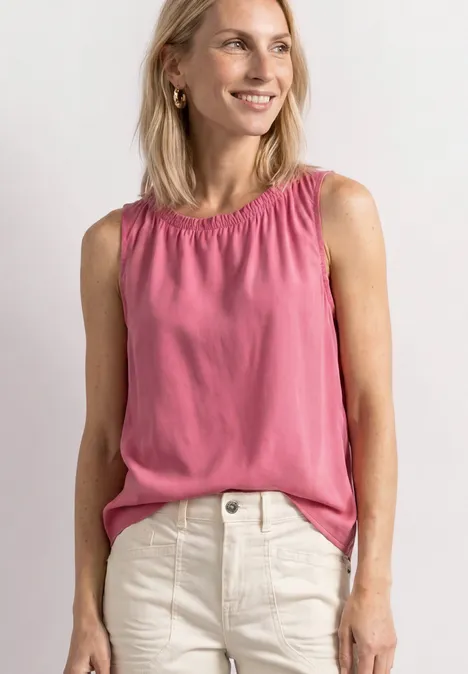 Blouse met gerimpelde ronde hals blush berry Vrouw in roze mouwloze top en witte jeans, glimlachend.