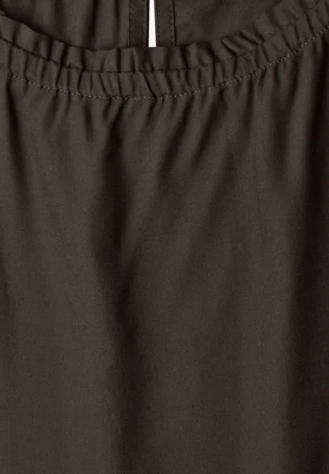 Close-up van een donker kledingstuk met elastische tailleband en zijsplit.