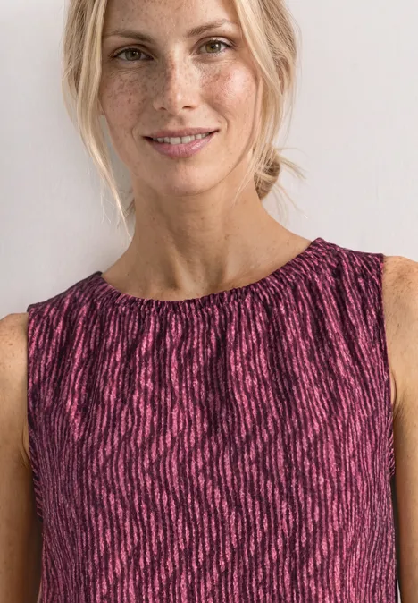 Femme porte un haut sans manches rose à motif noir.