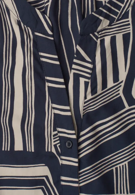 Detailaufnahme eines Kleidungsstücks mit marineblau-cremefarbenem, geometrischem Streifenmuster.