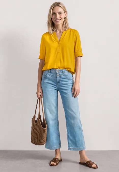 Blouse met korte mouwen, split in de hals en elastische zoom saffron yellow Frau in gelber Bluse, weiten Jeans, braunen Sandalen und geflochtener Tasche.