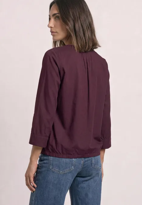 Femme en chemise violette et jean, vue de profil de dos