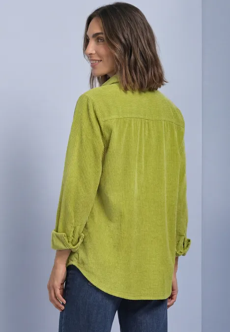 Langarm Hemdblsue aus Cord mit Knöpfen apple lime Frau im Rückenansicht trägt ein hellgrünes Cordhemd mit aufgekrempelten Ärmeln und Jeans.