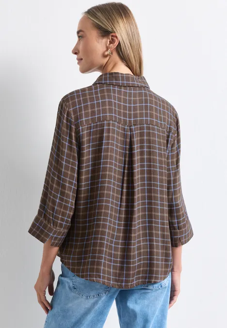 Frau von hinten in brauner karierten Bluse und Jeans.