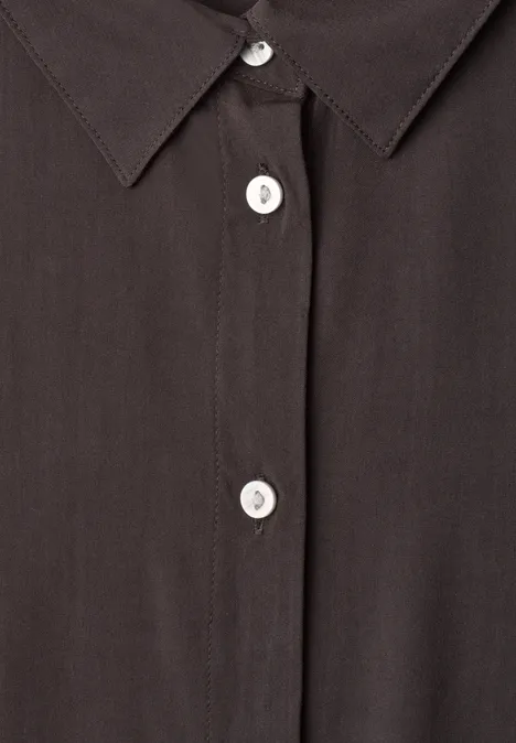 Overhemd met korte mouwen in effen kleur black coffee Close-up van een zwart overhemd met witte knopen en puntige kraag.