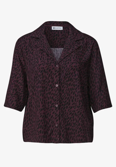 Lockere, lila Bluse mit schwarzem Punktemuster und Knopfleiste.