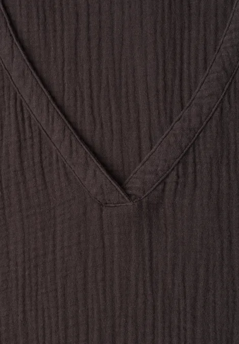 Chemisier à manches courtes, col en V et volants black coffee Gros plan d’un haut à col en V côtelé sombre avec détail de couture.