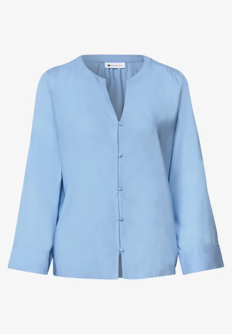 Hellblaue Bluse mit langen Ärmeln, V-Ausschnitt und durchgehender Knopfleiste.