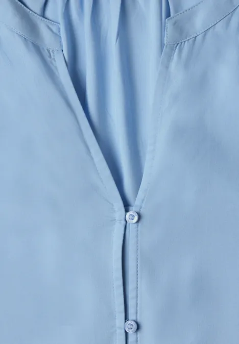 Hellblaues Hemd/Bluse im Detail, vorn leicht geöffnet mit zwei Knöpfen.
