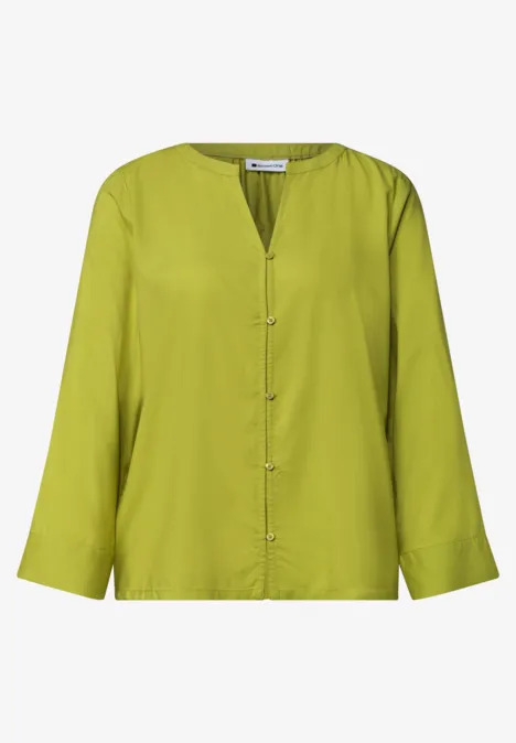 Blouse légère à manches longues vert vif, col en V et fermeture boutonnée.