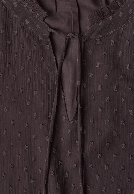 Dunkelbraune Bluse mit feinem Punktmuster und Bindeband am Rundhalsausschnitt.