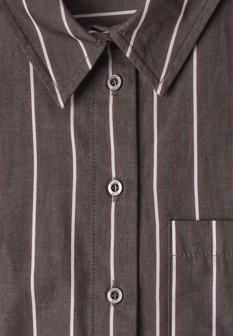 Gros plan sur une chemise gris foncé à fines rayures blanches et rouges, boutons et poche poitrine.