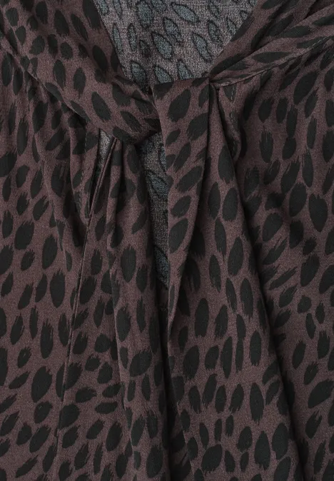 Braune Bluse mit schwarzem Blattmuster und dekorativem Knotendetail am Ausschnitt.