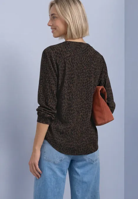 Frau von hinten, schwarzes Shirt mit braunem Leomuster, blaue Jeans, hält cognacfarbene Tasche.