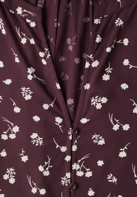 Dunkellila Bluse mit feinem weißen Blumenmuster, geknöpftem V-Ausschnitt und leichter Raffung.