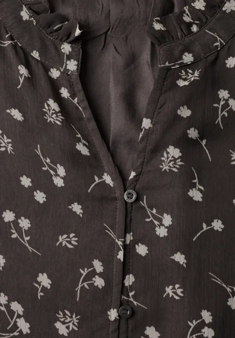 Zwarte stof met fijne witte bloemenprint en zwarte knopen.