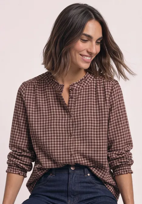 Blouse met lange mouwen, ronde hals en ruches warm blush Frau in braun-kariertem Hemd, lächelt in die Kamera.