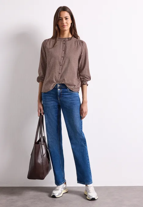 Blouse met lange mouwen, ronde hals en ruches warm blush Frau in lockerem braunem Hemd, geraden Jeans, weißen Sneakern und großer dunkelbrauner Tasche.