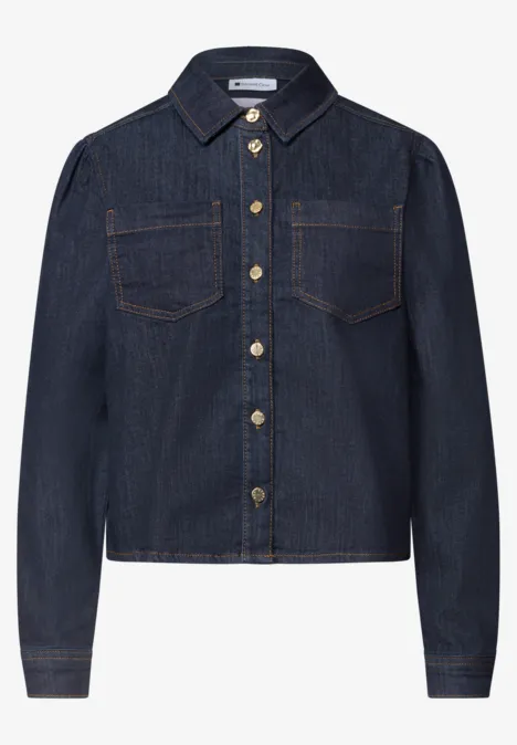 Dunkelblaue Jeansjacke mit Hemdkragen, Brusttaschen und goldfarbenen Knöpfen.