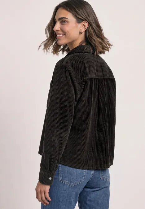 Overhemd van corduroy met borstzakken black coffee Eine lächelnde Frau in seitlicher Ansicht trägt eine braune Cordjacke und blaue Jeans.