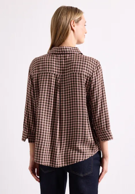 Bluzka z rękawami 3/4 w kratkę warm blush Kobieta od tyłu w brązowo-czarnej koszuli w kratę z rękawami 3/4, blond włosy.