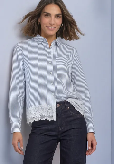 Chemisier à manches longues, rayé et orné d'une bordure en dentelle northern blue Eine Frau trägt ein blau-weiß gestreiftes Hemd mit Spitzenbesatz und Jeans und lächelt.