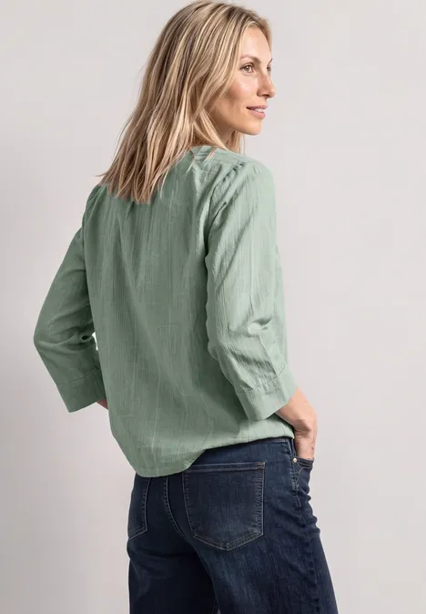Frau im Profil mit grüner Bluse und blauer Jeans
