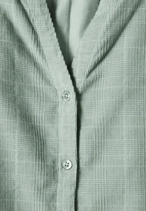 Grünes Hemd mit feinem Karomuster und Knopfleiste, Detailaufnahme von Vorderseite und Kragen.