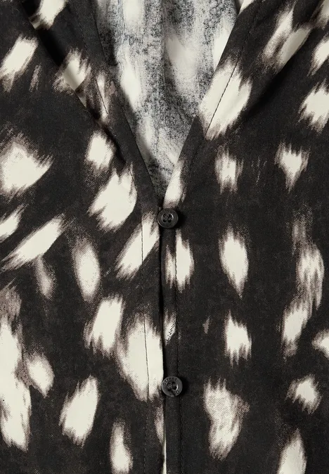 Cardigan noir et blanc à motifs tachetés irréguliers rappelant un imprimé animal.