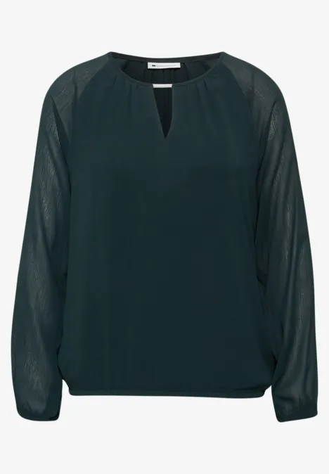 Donkergroene chiffonblouse met lange, transparante mouwen en kleine V-halsopening.