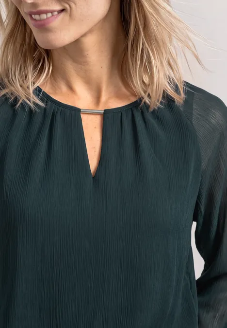 Donkergroene blouse met fijne structuur, lange mouwen en een kleine split in de hals met metalen sierstrip.