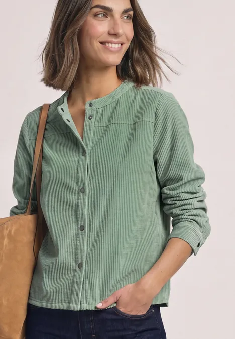 Chemisier à manches longues en velours côtelé avec coutures décoratives eucalyptus green Lächelnde Frau in grüner Hemdjacke mit Beutel über der Schulter.