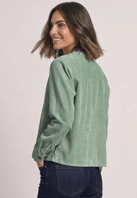 Chemisier à manches longues en velours côtelé avec coutures décoratives eucalyptus green Frau von hinten in grüner Cordjacke mit langärmligem Hemd, schaut lächelnd zurück.
