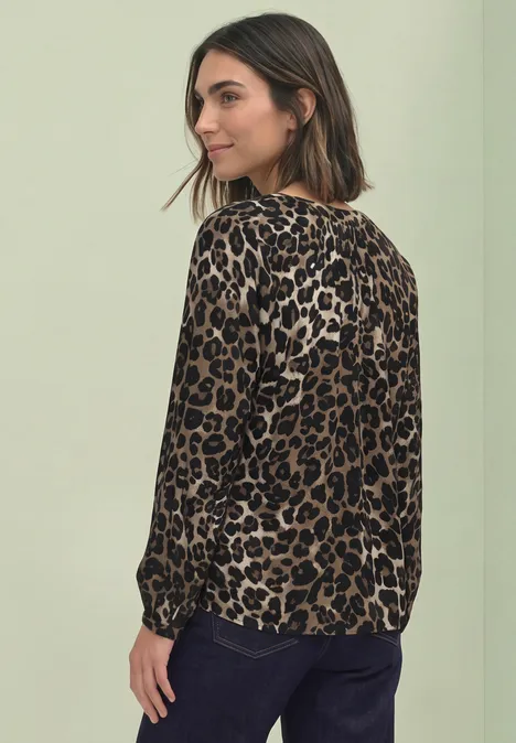 Blouse met lange mouwen, splitnek en luipaardprint Black Een vrouw draagt een leopardprint shirt met lange mouwen en spijkerbroek en kijkt over haar schouder.
