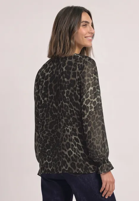 Tunika aus Chiffon mit Cut-Out-Detail Black Frau trägt grüne, semi-transparente Bluse mit Animal-Print, schaut lächelnd über die Schulter.