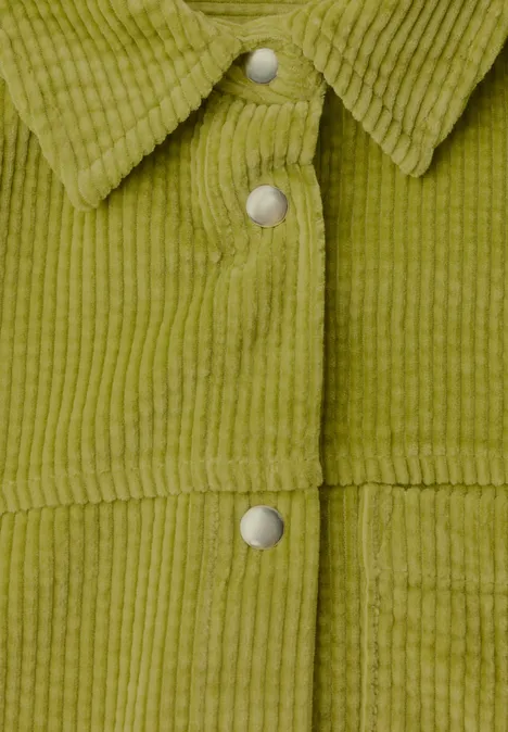 Nahaufnahme einer olivgrünen Cordjacke mit Stehkragen und silbernen Druckknöpfen.