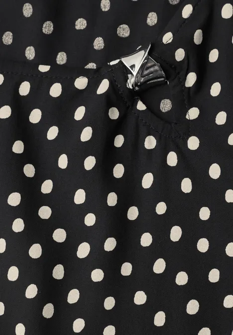 Schwarzer Stoff mit weißen Polka-Dots und kleiner Zierschleife.