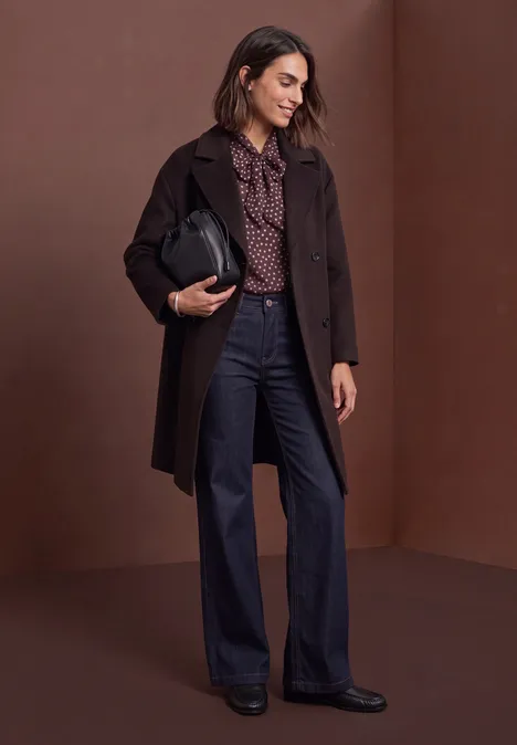 Haut-blouse en chiffon avec nœud décoratif berry plum Femme en manteau marron, chemisier à motifs et jean large, tenant un sac noir.