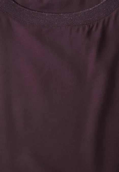 Blouse courtes manches à col rond et bandes pailletés berry plum Gros plan sur l’encolure d’un t-shirt couleur baie, en tissu fin légèrement brillant.