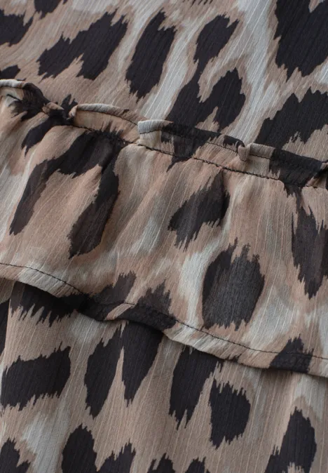 Nahaufnahme eines Leopardenmusters auf leichtem, chiffonähnlichem Stoff mit Rüschenkante.