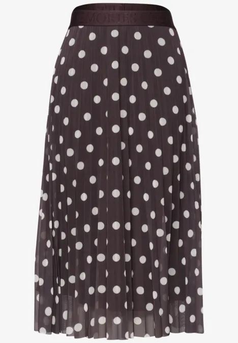 Ein knielanger, plissierter Rock mit weißen Polka-Dots auf dunkelbraunem Stoff.