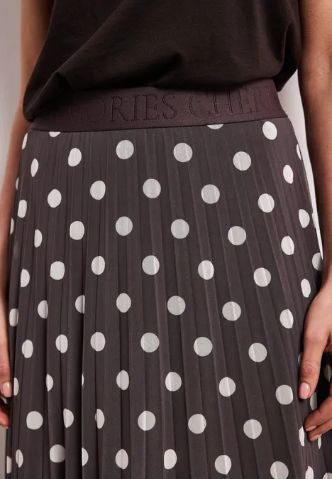 Plissierter, dunkelgrauer Midi-Rock mit großen weißen Punkten, elastischem Bund, kombiniert mit schlichtem schwarzen Top