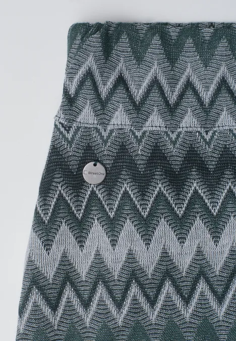 Gebreid grijs kledingstuk met zigzagpatroon en ronde knoop