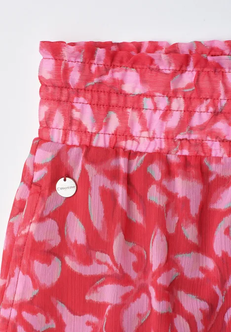 Rotes, geblümtes Kleidungsstück mit gerafftem Bund und rundem Metall-Emblem