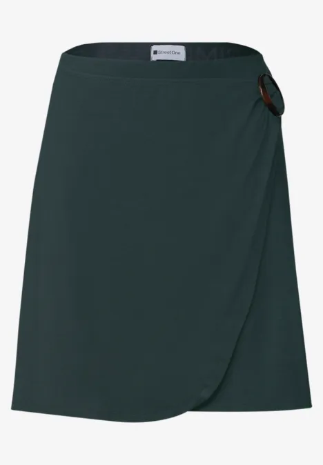 dunkelgrüner Wickelrock mit rundem Schnallenverschluss, knieumspielende Länge
