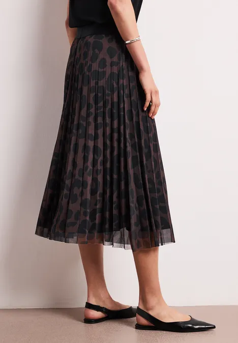 Donkere geplisseerde midirok met luipaardprint, gecombineerd met zwarte slingback pumps.